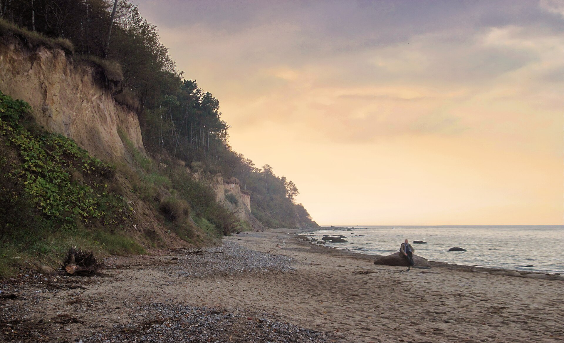 Cliffed coast with resting man near sunset.JPG